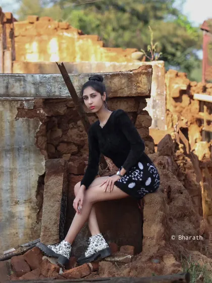 A full-length seated portrait, highlighting the entire look in the context of the unique location.