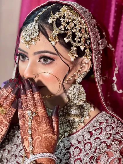 A beautiful, shy pose that highlights the detailed henna and the stunning bridal jewellery.