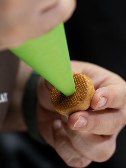 Filling a small, intricate cookie. Precision is key in pastry, and our instructors guide you through every detailed step.