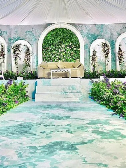 An ethereal and dreamy stage design. We used a watercolor-effect backdrop, a green floral arch, and a pathway lined with lavender for a truly unique and artistic wedding setup.