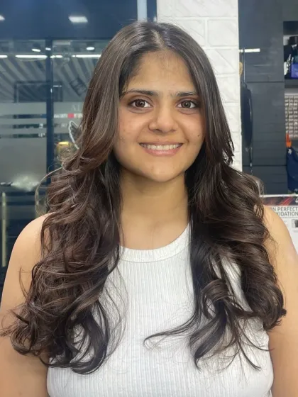 A happy client showing off her new hairstyle, which features soft, face-framing layers and gentle waves for a natural and pretty look.