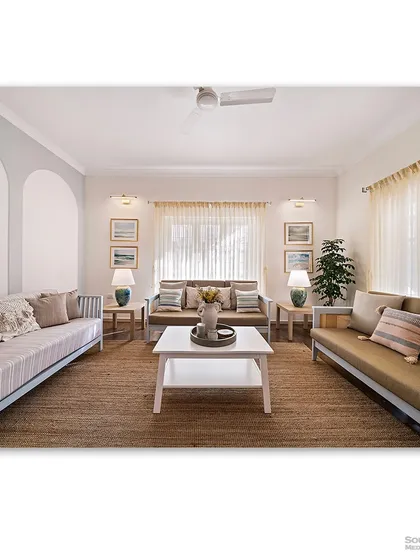A bright and airy living room with an ocean-inspired color palette. The light wood furniture, jute rug, and sheer curtains create a relaxed, coastal vibe that is both comforting and stylish.