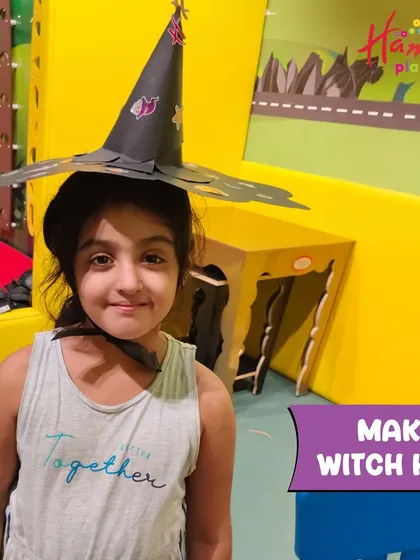 A young girl proudly wears the witch hat she made. Our Halloween workshops are full of magical crafts that kids can wear and play with.