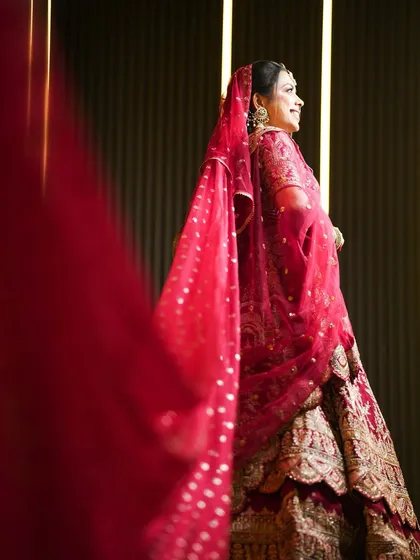 A smiling bridal portrait, with the red veil adding a soft frame to her face.