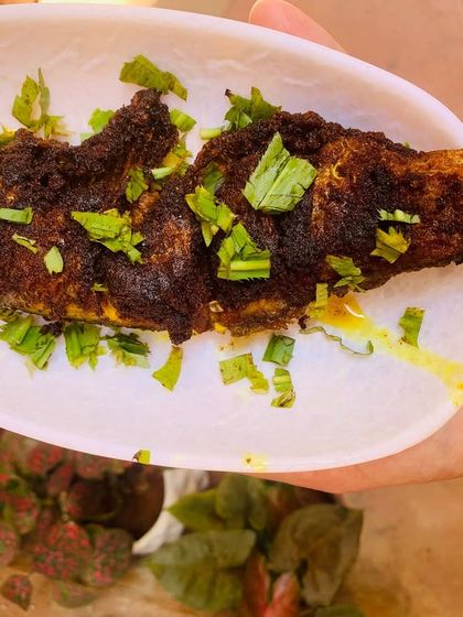 A perfectly fried river fish, crispy on the outside and soft on the inside, garnished with fresh herbs.
