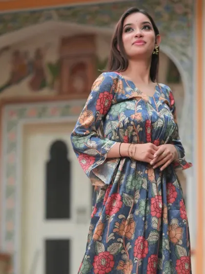 A floral print dress with bell sleeves, set against a historic backdrop. The muted colors and flowing silhouette give it a romantic, timeless feel.