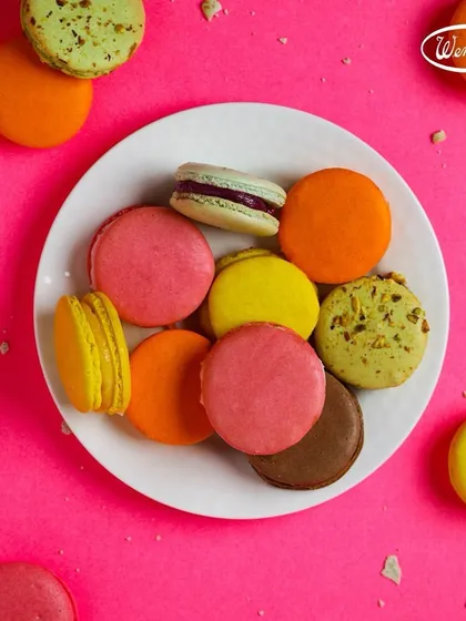 A colourful plate of our assorted macarons. The bright pink background highlights the beautiful colours of these delightful French confections.