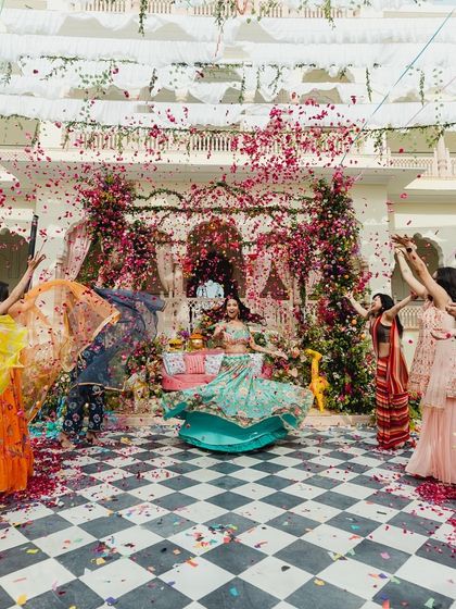 A vibrant Mehendi performance. The bride's entry was celebrated with a shower of flower petals by her bridesmaids, creating a colorful and joyous start to the festivities at this beautiful Jaipur wedding.