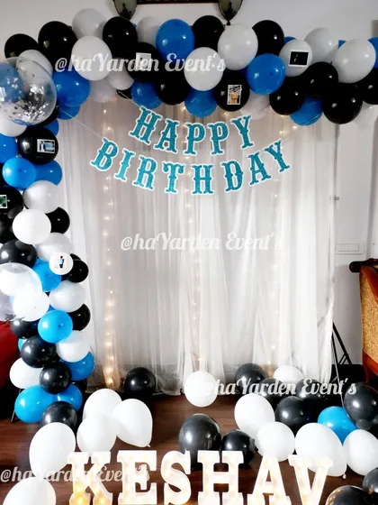 A simple and clean balloon arch in blue, black, and white. The 'Happy Birthday' banner and marquee letters make it a complete and personal setup.