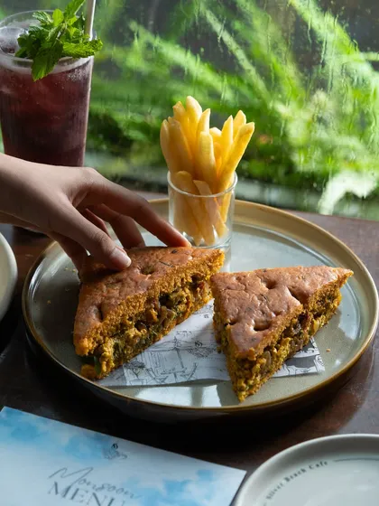 A savory sandwich with a side of fries, shot against a rainy window. This creates a cozy, comforting mood.
