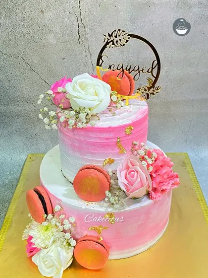 A stunning two-tier engagement cake in shades of pink. I decorated this one with fresh flowers and delicate macarons for an extra touch of elegance.