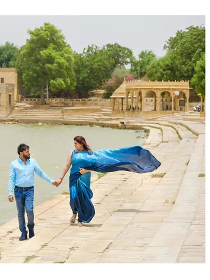A beautiful shot of the couple walking by Gadisar Lake in Jaisalmer. Her blue saree flows in the wind, creating a stunning sense of movement.