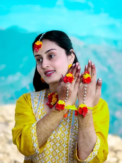A happy bride-to-be, adorned in yellow and floral jewelry for her pre-wedding ceremony.