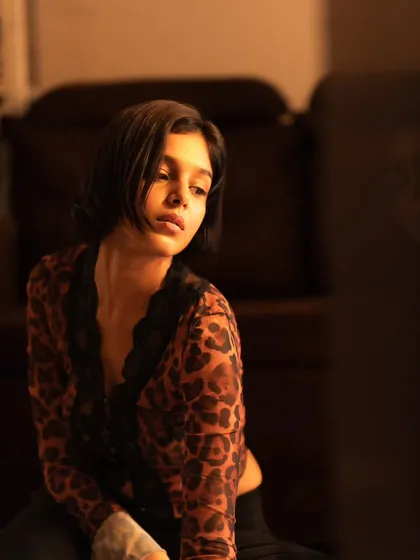 A pensive, looking-away shot that uses the warm ambient light of the room to create a cinematic feel.