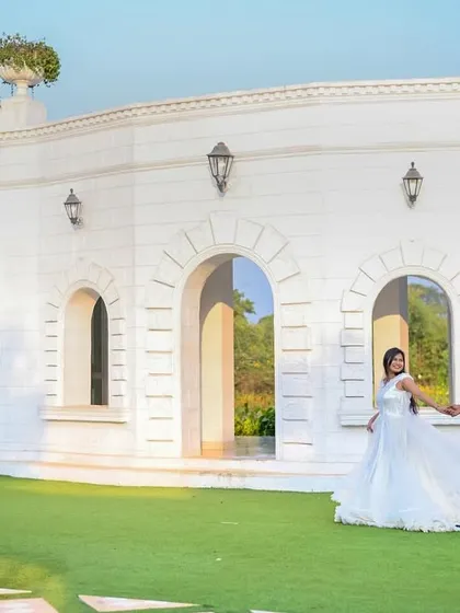 A wide shot of a couple taking a romantic stroll in front of a magnificent white building. This pre-wedding photo has a timeless, elegant feel, like a scene from a classic movie.