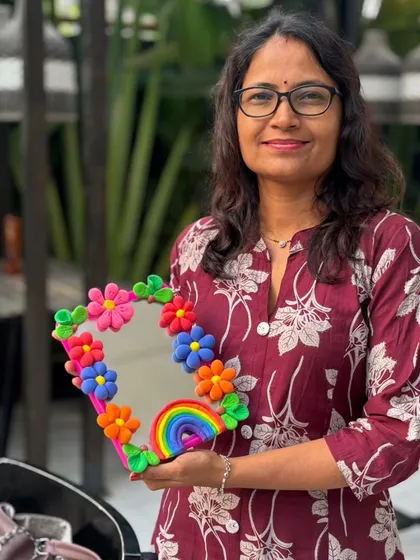 A participant proudly displays her colorful clay mirror, complete with a rainbow. A cheerful, handmade addition to any room.