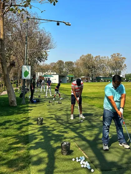 A line of golfers on the mats, with the shadows growing long on a sunny afternoon.