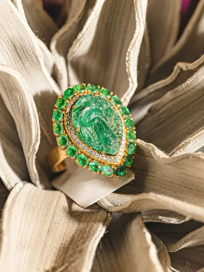 This ring is a tribute to ancient artistry, featuring a Ganesha carved from a single, beautiful emerald. Surrounded by a halo of smaller emeralds and diamonds, it is a piece that carries deep meaning and exquisite craftsmanship.