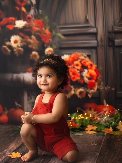Her sweet, shy smile is just everything. This little girl's personality shines in this beautiful fall-themed setting with pumpkins and flowers.