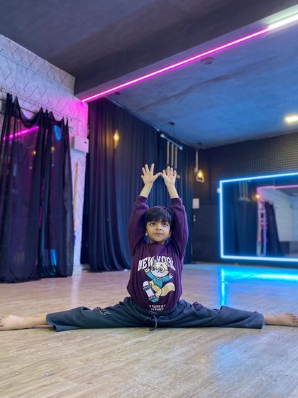 Flexibility is key for any serious dancer. This student showcases a perfect center split, a result of consistent practice in our flexibility and conditioning sessions.