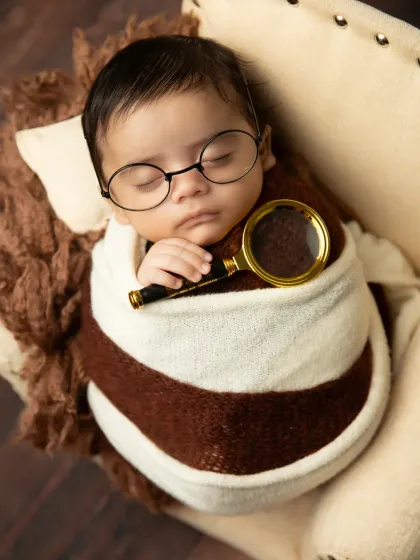 This pose shows the baby snugly wrapped and holding a magnifying glass, ready to discover the world in their dreams.