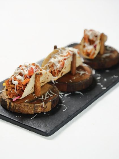 Taco, but make it Indian. We serve pulled jackfruit in a soft phulka shell, drizzled with lime cream and a pop of salsa for a dish that is bold, bright, and unmistakably inventive.