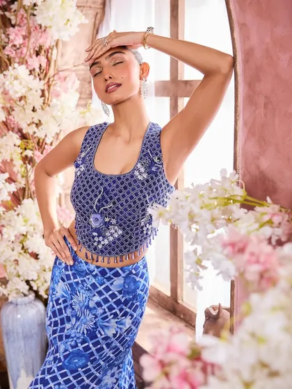 A beautiful, relaxed pose showing off the detailed blue top. The makeup features a soft, shimmery eyeshadow and glowing skin, creating an ethereal and glamorous feel.