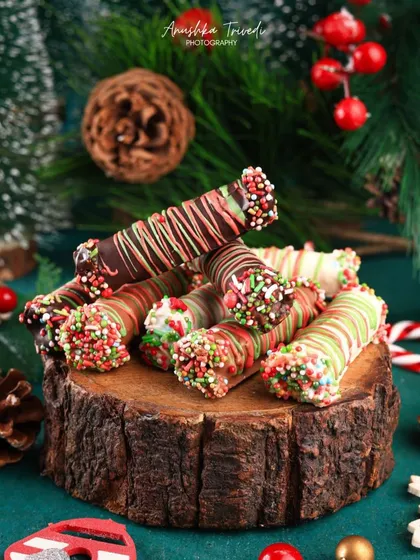 Christmas-themed chocolate cigar rolls, drizzled and sprinkled in festive colours. I styled them on a rustic log slice to give it a cozy, winter-cabin feel.