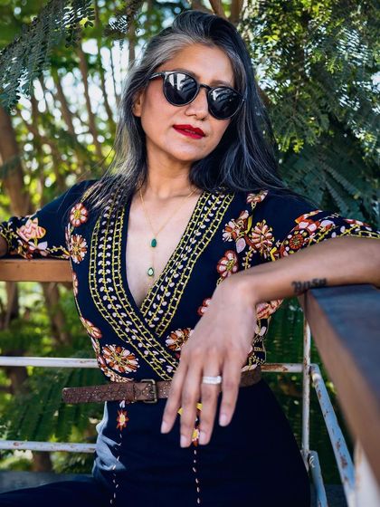 A close-up of the floral jumpsuit, accessorized with sunglasses and a delicate necklace.