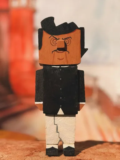 A frontal view of the Maganlal Meghraj wooden collectible. The sharp lines and blocky form are part of the unique artistic style I developed for this entire cinematic series.