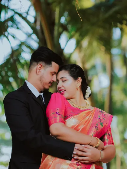 A warm and affectionate embrace. The bride's beautiful pink saree stands out against the soft green background, creating a stunning visual contrast.