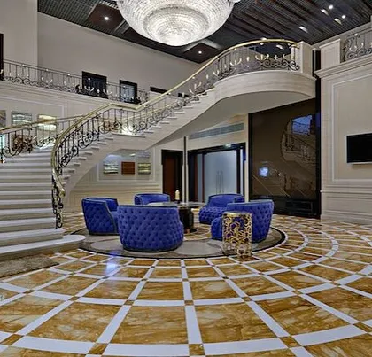 A throwback to the A-Class Marble showroom, a space where luxury and innovation converge. The design features a grand semi-circular staircase and radial flooring patterns in burning gold and white marble, creating a sense of opulence and movement.