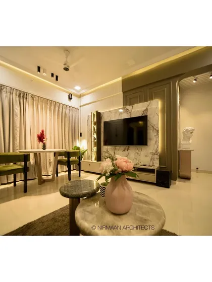 The dining area in this modern classic living room is positioned to take advantage of natural light. The marble-clad TV unit and elegant furniture create a cohesive and sophisticated look.