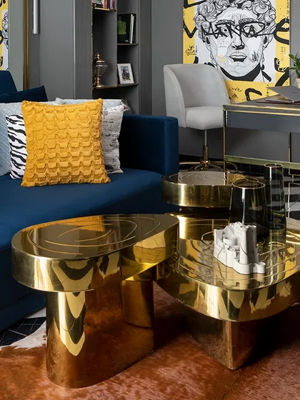 For us, the magic is in the details. This custom-designed coffee table, with its fluid form and polished gold finish, is a perfect example of our bespoke furniture craft. Paired with a deep blue sofa and bold artwork, it becomes a functional sculpture that elevates the entire living space.