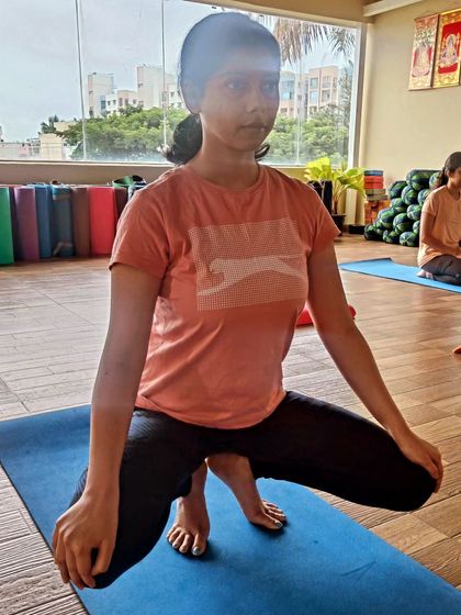 A student practices a toe-balancing squat. This pose challenges your balance, strengthens your feet and ankles, and requires a great deal of focus and concentration.