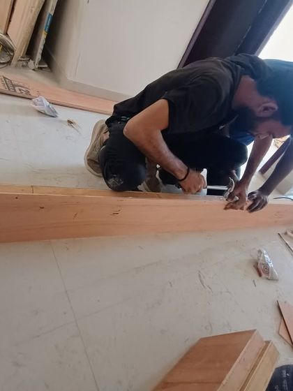 A close-up of the detailed woodwork our team performs. A carpenter is carefully sanding a wooden plank, a crucial step to ensure a smooth and flawless finish for the furniture.