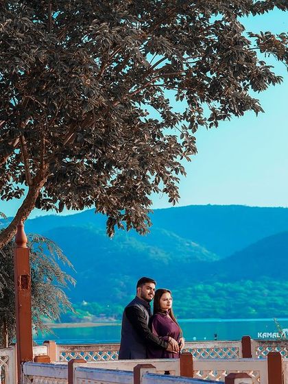 A beautiful landscape shot capturing the couple against the serene backdrop of Jaipur's hills and lakes, showcasing the natural beauty of the region.