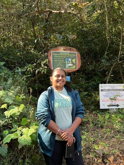 A trekker posing at the forest department sign at the start of the Kurinjal trail.