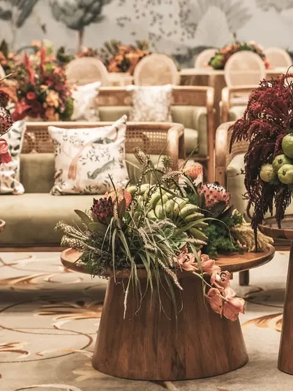 A seating area at the 'Orchard of Life' naming ceremony, with beautiful floral arrangements on wooden tables.