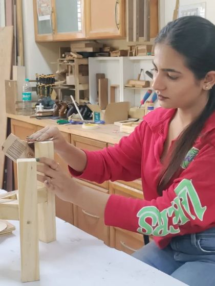 A student sanding the legs of a small stool. Finishing is just as important as construction, and it's a key part of the process we teach.