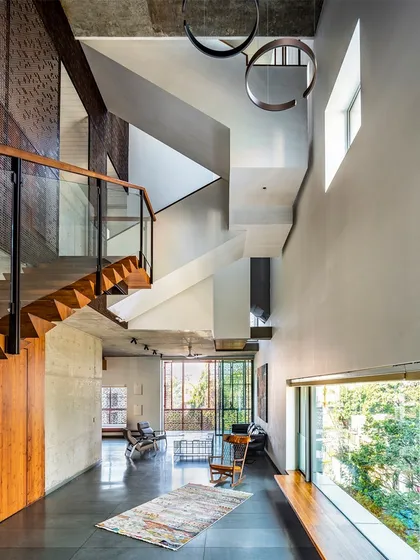 This view from the upper level of J-House shows the vertical volume of the space, with staircases and bridges connecting different areas, creating the feeling of a 'bungalow in the sky'.