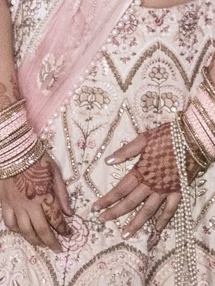 This shot focuses on the intricate embroidery of the lehenga skirt, complemented by the client's henna and matching pink bangles.