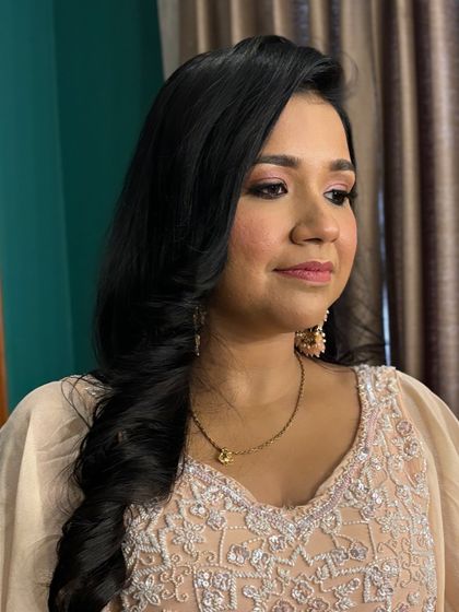 A beautiful client in a peach-colored lehenga. The makeup is soft and romantic, with pink and peach tones on the eyes and cheeks.