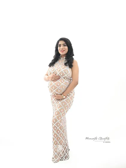 A clean and minimalist high-key portrait. The all-white background makes the sparkling gown and the mom-to-be's beautiful bump the absolute focus.