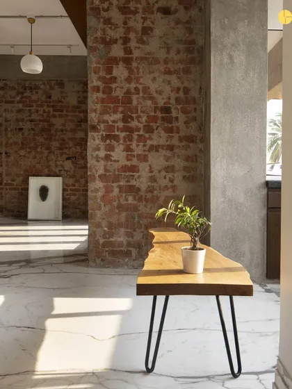 A simple wooden bench against a raw concrete and brick wall in the unfinished 'Canvas' apartment. Even in its rawest state, the interplay of materials tells a story.