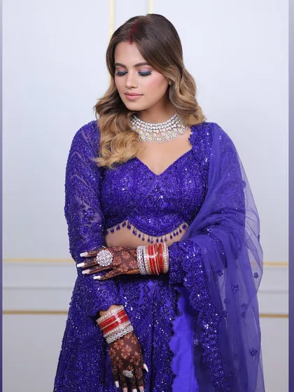 A bride looking elegant in a royal blue lehenga, with her hands showcasing a deep, rich henna stain. The color perfectly complements her festive attire.