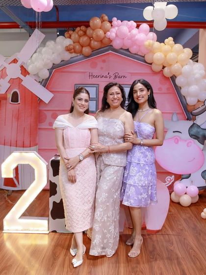 Guests pose in front of the adorable "Heerina's Barn" backdrop, complete with a windmill, cow, and sheep cutouts.