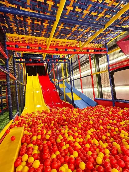 Welcome to our multi-level play paradise. This wide view shows our exciting slides plunging into a massive ball pit, just a glimpse of the adventure that awaits your children in our fully air-conditioned, safe play zone.
