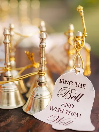A close-up of the beautiful custom bells for guests. The tag "Ring the Bell and Wish them Well" adds a charming and interactive element to the ceremony.
