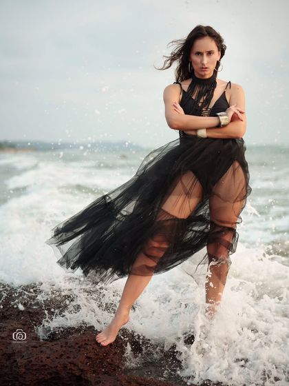 A fierce and dramatic pose with the model standing in the surf. The splashing water adds energy and movement to this striking beach portrait.